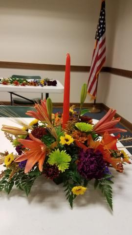 Photo with fall colored flowers and foliage and tapered candle centerpiece.