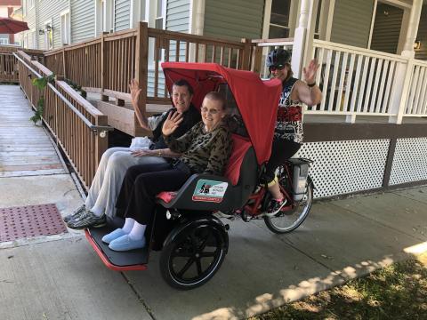 Two seniors on a covered seat of a trishaw.