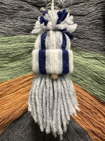 Gnome ornament made of white, light gray, and dark blue yarn.