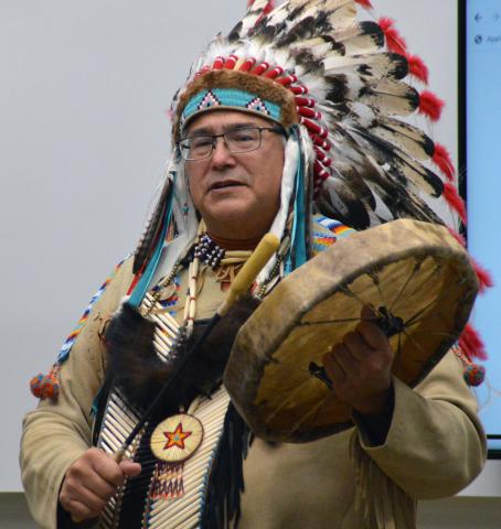 A Ho-Chunk Nation Elder in traditional headdress with a traditional drum