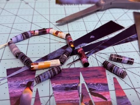 Rolled magazine pieces on string in various colors on a cutting mat