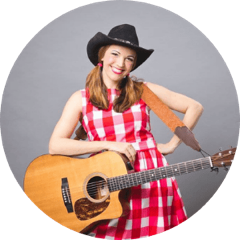 Woman wearing a red plaid dress, a cowboy hat and holding a guitar
