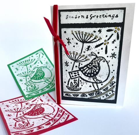 three holiday cards, red, green and black with a hand carved design
