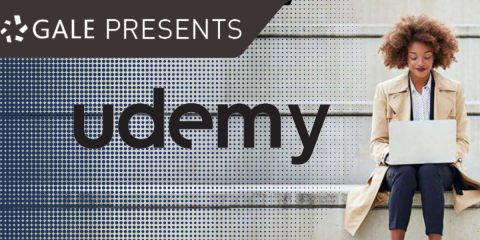 woman seated on a ledge outside using a laptop