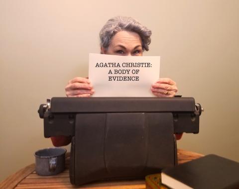 Actress Debra Ann Miller dressed as Agatha Christie hides behind an antique typewriter with a sheet of paper pulled out with the title of the program