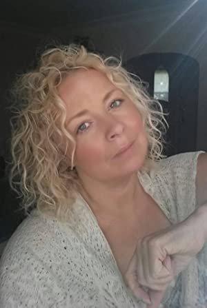 a woman with curly blond hair sitting close to the camera in a dark room