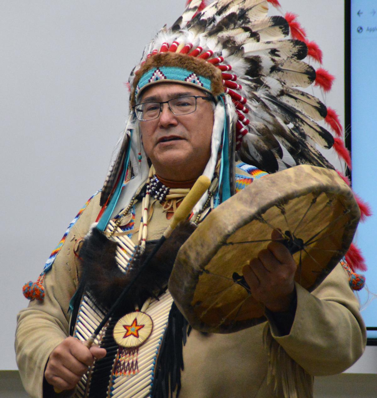 A Ho-Chunk Nation Elder in traditional headdress with a traditional drum