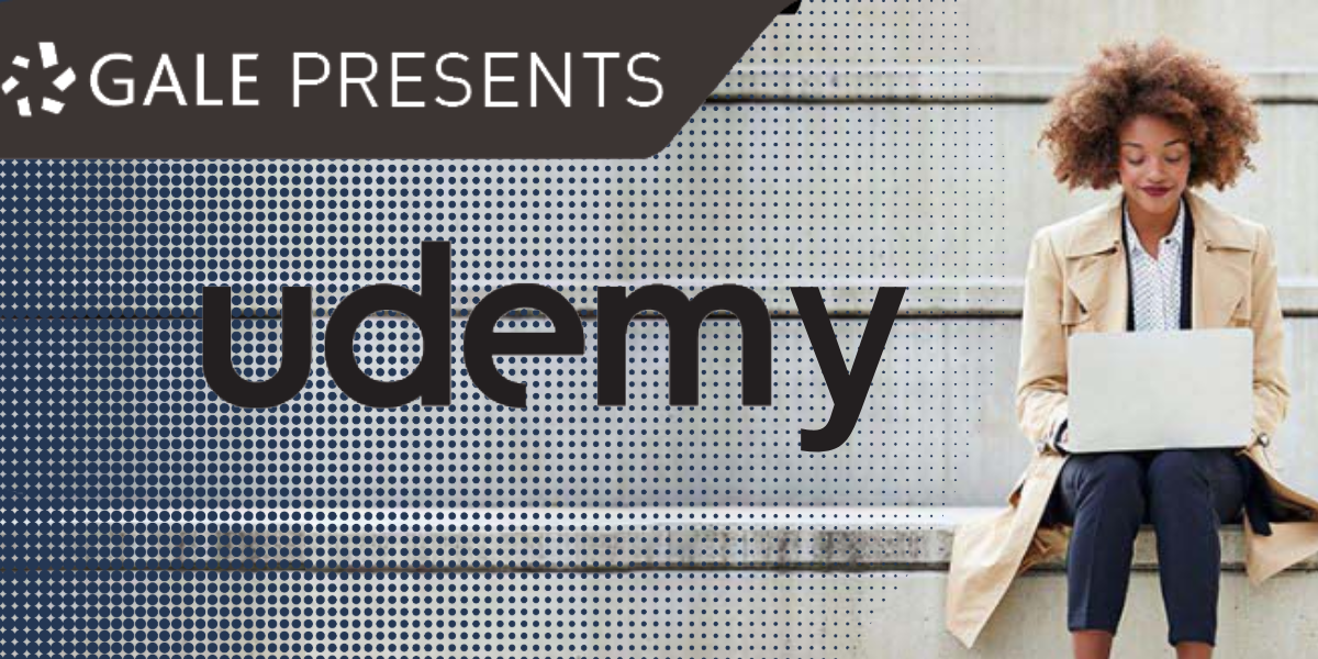 woman seated on a ledge outside using a laptop